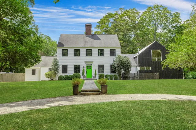 a front view of a house with a garden and trees