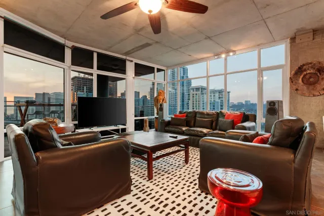 a living room with furniture a flat screen tv and a floor to ceiling window