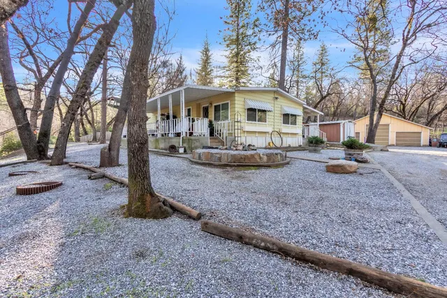 a front view of a house with a yard covered with trees