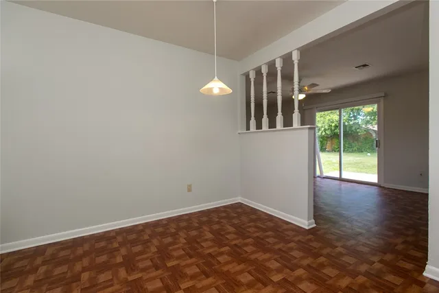 a view of an empty room with wooden floor and windows