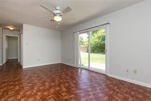 a view of an empty room with window and a kitchen view