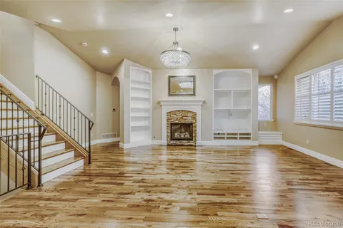 a view of an empty room with wooden floor fireplace and a window
