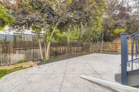 a view of backyard with large trees and wooden fence
