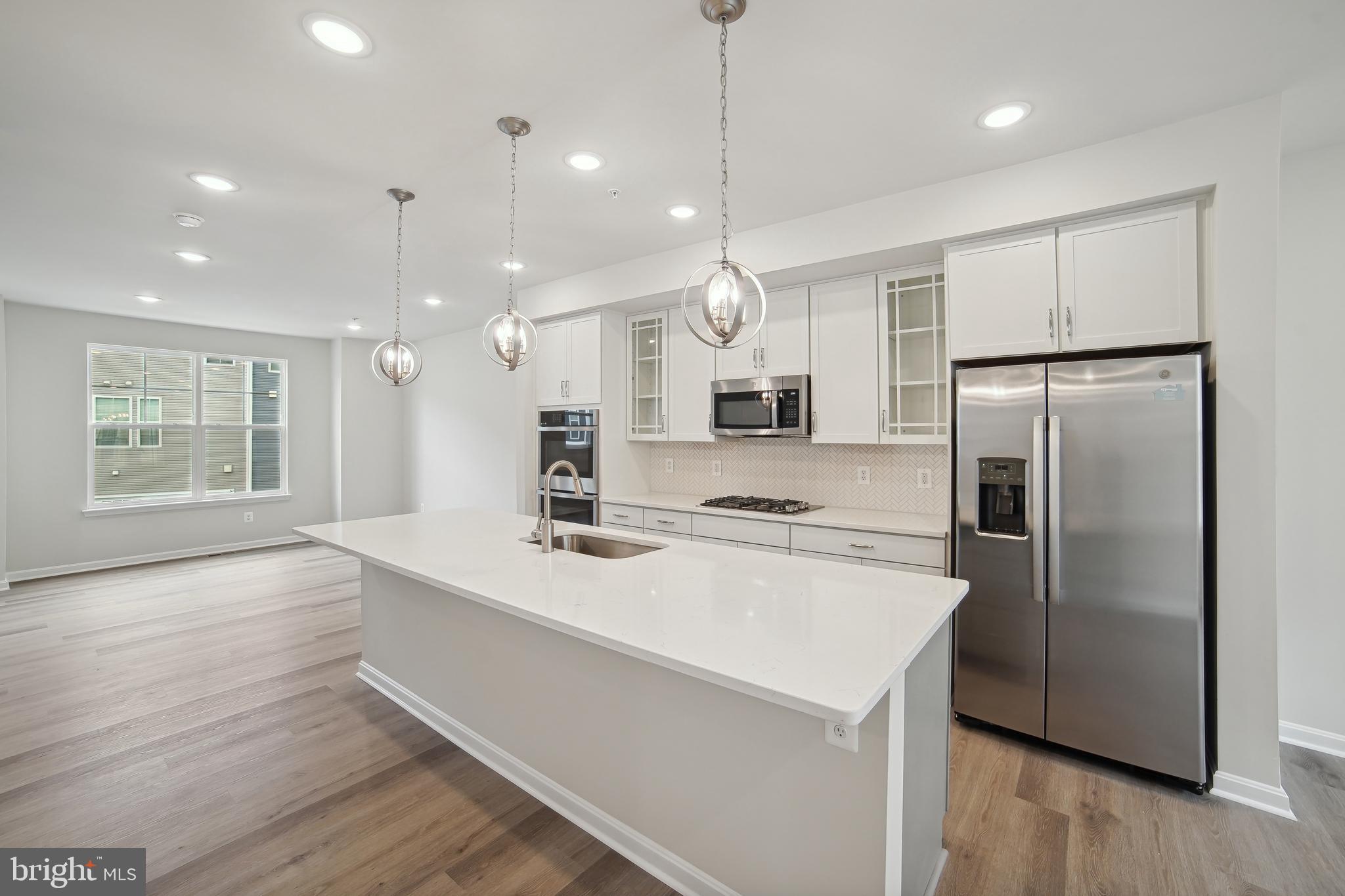 2513 Gatwick Lane Frederick, MD 21701 - Photo 3 of 14 a kitchen with stainless steel appliances kitchen island granite countertop a refrigerator a sink dishwasher a stove and white cabinets with wooden floor