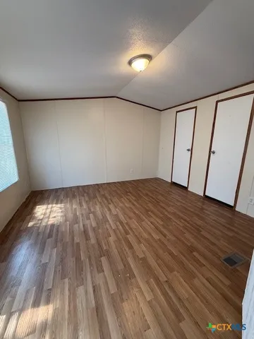 a view of empty room with wooden floor