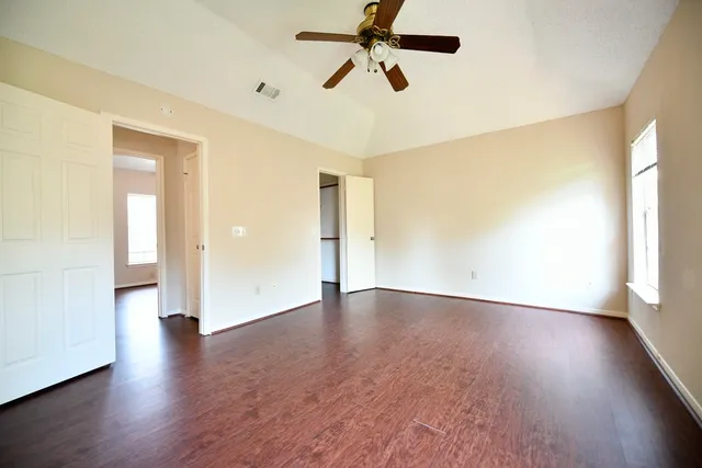 a view of empty room with wooden floor and fan