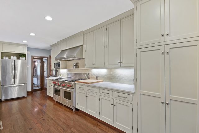 a kitchen with stainless steel appliances white cabinets and wooden floors
