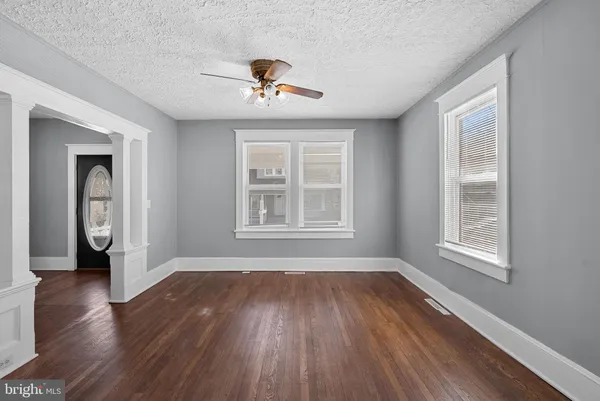 a view of empty room with wooden floor and fan