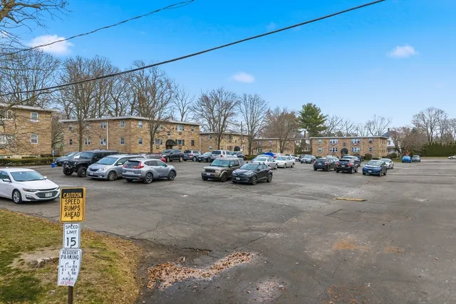 a view of road with card parked on side and retail shops
