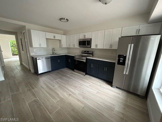 1555 Blue Point Avenue, Unit 2 Naples, FL 34102 - Photo 2 of 10 Kitchen featuring white cabinetry, sink, stainless steel appliances, and light wood-type flooring