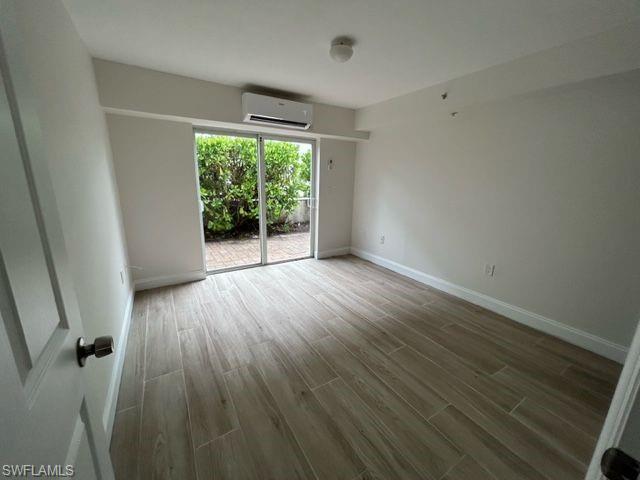 1555 Blue Point Avenue, Unit 2 Naples, FL 34102 - Photo 5 of 10 Spare room featuring hardwood / wood-style flooring and a wall unit AC