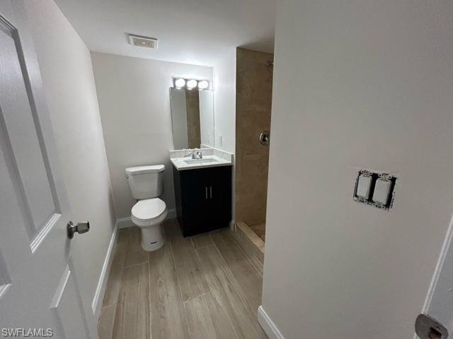 1555 Blue Point Avenue, Unit 2 Naples, FL 34102 - Photo 7 of 10 Bathroom featuring a shower, vanity, hardwood / wood-style flooring, and toilet