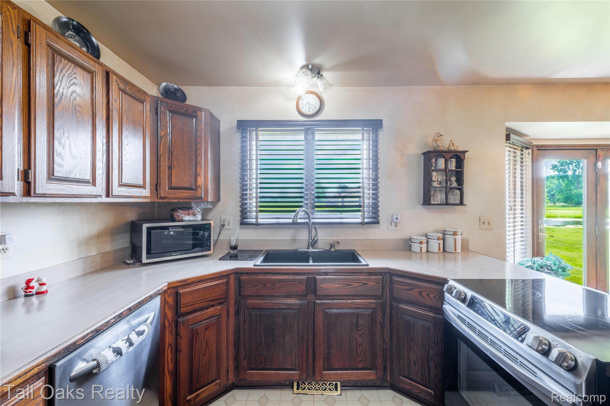 79330 Capac Road Armada, MI 48005 - Photo 25 of 42 Kitchen featuring wood cabinetry, stainless steel dishwasher, an integrated sink, corner window with blinds, and French doors to the exterior