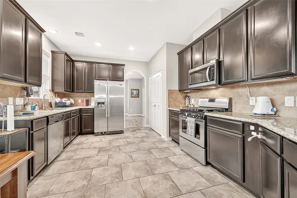 a kitchen with stainless steel appliances granite countertop a stove top oven and sink