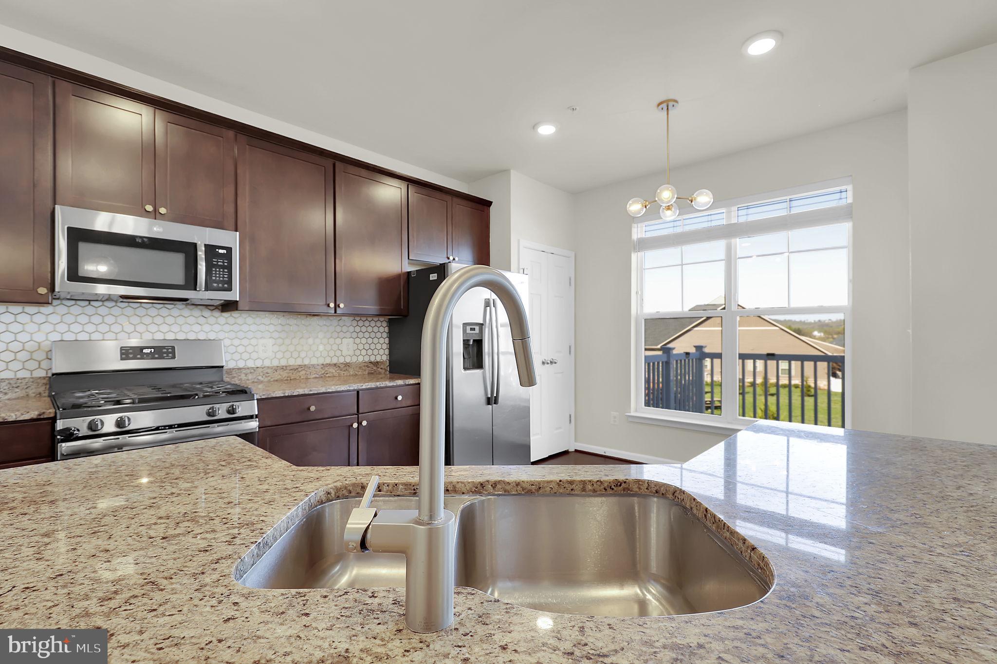 5906 Krantz Drive Frederick, MD 21703 - Photo 11 of 40 a kitchen with kitchen island granite countertop a sink a counter top space appliances and cabinets