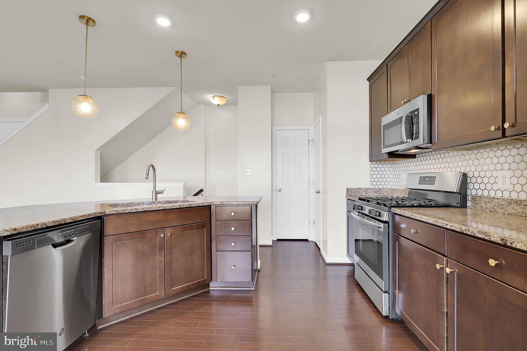 5906 Krantz Drive Frederick, MD 21703 - Photo 10 of 40 a kitchen with stainless steel appliances granite countertop a sink a stove and a wooden floors