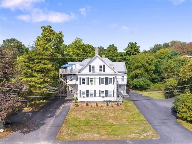 a view of a house with a small yard and large trees