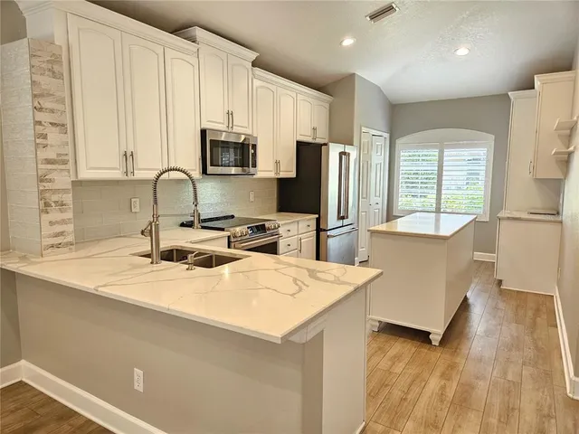 a kitchen with stainless steel appliances a refrigerator a sink a stove a microwave and wooden cabinets