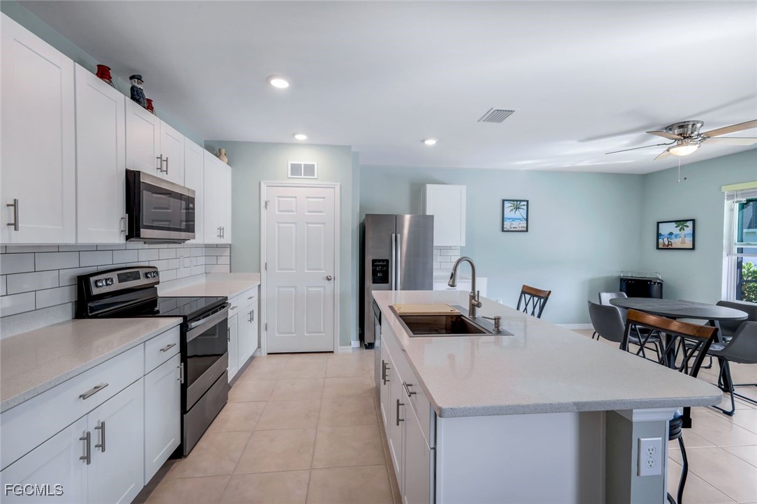566 Corrientes Circle Punta Gorda, FL 33983 - Photo 13 of 36 a kitchen with stainless steel appliances kitchen island granite countertop a stove a sink a microwave and a refrigerator