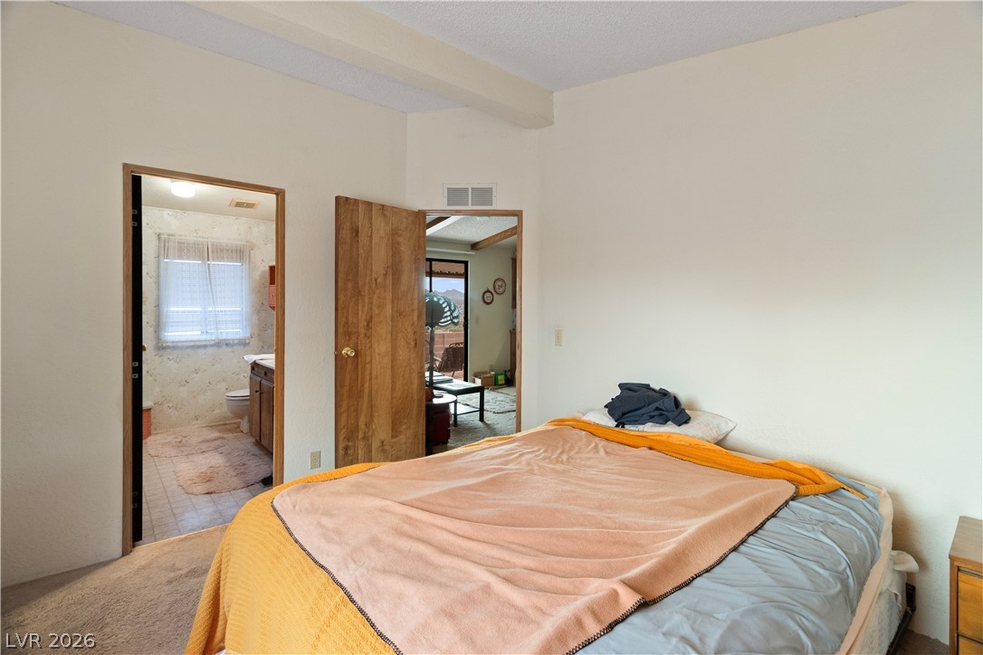 1609 Cajon Court Laughlin, NV 89029 - Photo 17 of 69 Primary Bedroom with beam ceiling, ensuite bathroom, and carpet