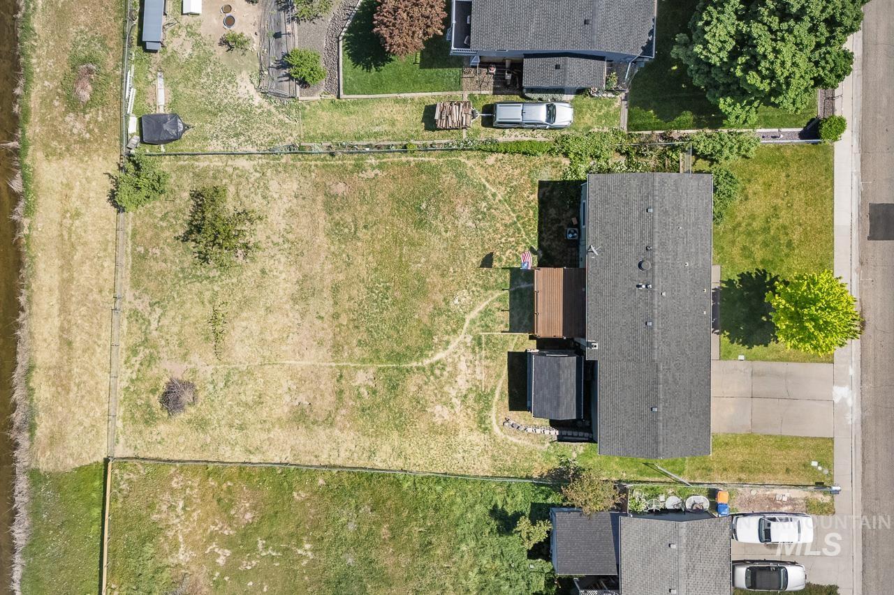 10178 West Fox Ridge Drive Boise, ID 83709 - Photo 32 of 36 Expansive property featuring a large land parcel, a residential structure with a dark shingle roof, a paved driveway, and a wooden deck