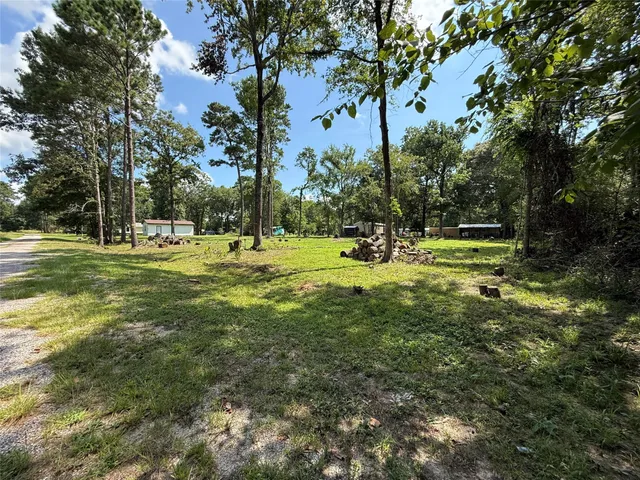 a big yard with lots of green space and trees in the back