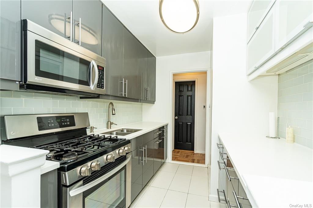 Kitchen featuring stainless steel appliances, sink, tasteful backsplash, and light tile flooring
