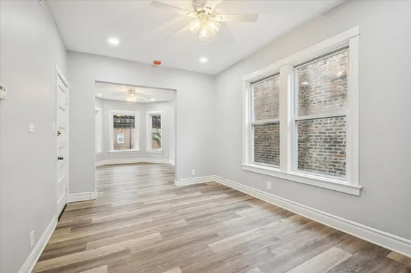 a view of an empty room with wooden floor and a window