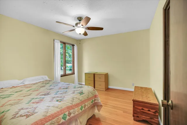 an empty room with wooden floor chandelier fan and windows
