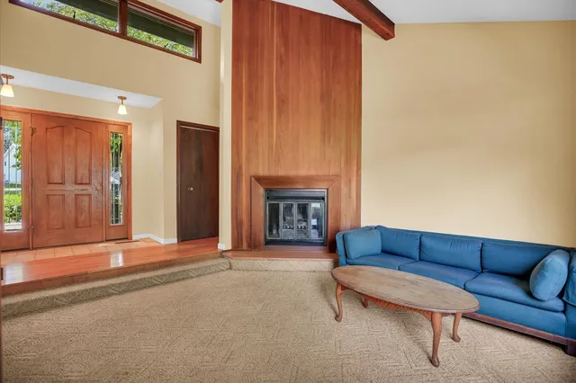a living room with a furniture a fireplace and a large window