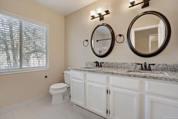 a bathroom with a granite countertop toilet a sink and a mirror