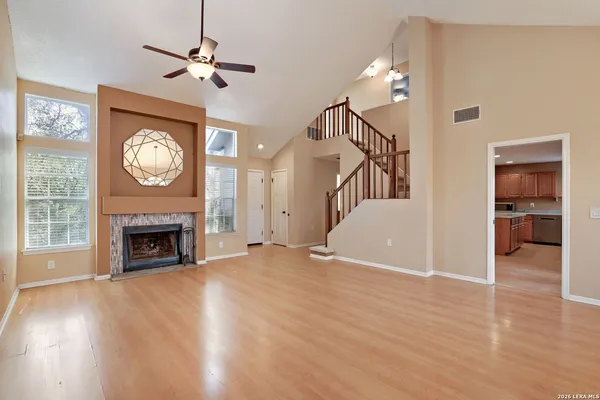 a view of an empty room with wooden floor fireplace and a window