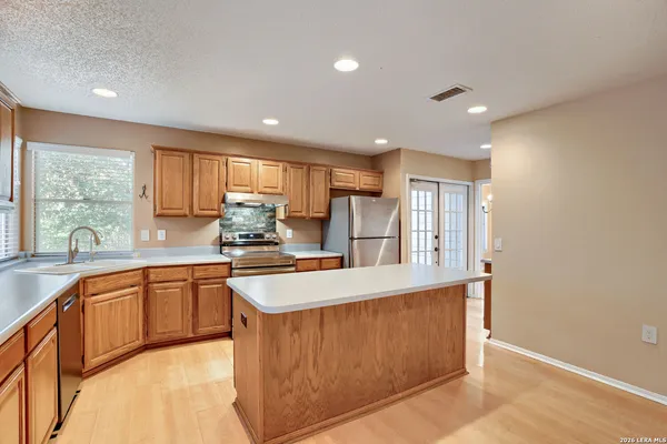 a large kitchen with stainless steel appliances granite countertop a large counter top a sink a stove and a refrigerator