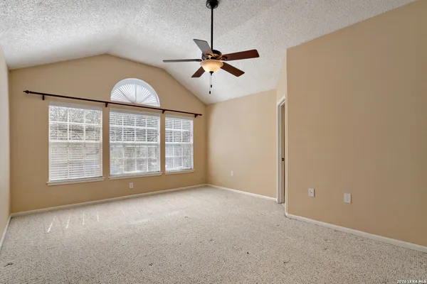 an empty room with windows and fan