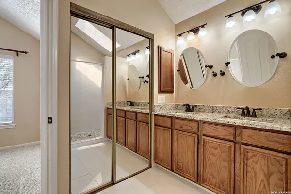 a bathroom with a granite countertop double vanity sink and mirror