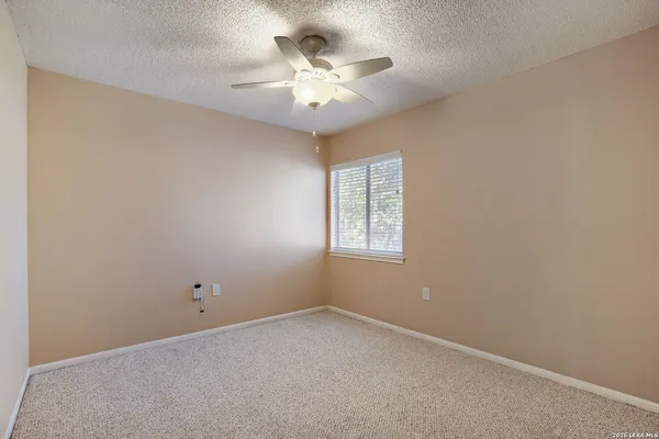an empty room with a ceiling fan and window