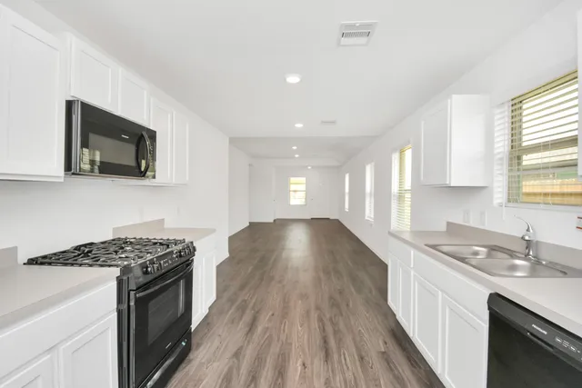 a kitchen with a sink stove top oven and cabinets
