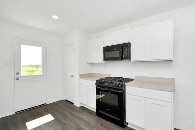 a kitchen with stainless steel appliances a stove a microwave and white cabinets