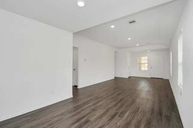 an empty room with wooden floor and window