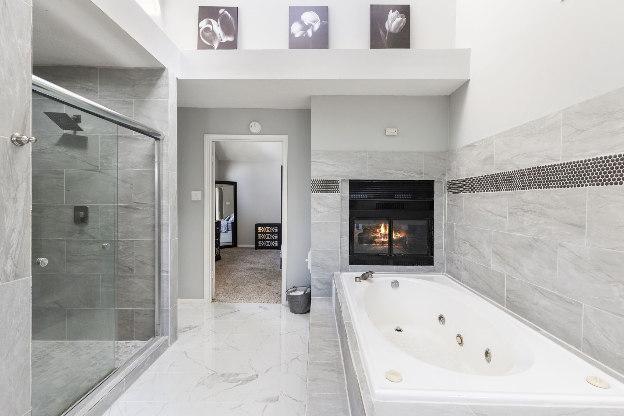2110 Paso Rello Drive Houston, TX 77077 - Photo 29 of 41 This bathroom features a luxurious jetted tub with a cozy fireplace, a spacious glass-enclosed shower, and elegant tile flooring. The room is brightened by natural light and creates a serene and inviting atmosphere.
