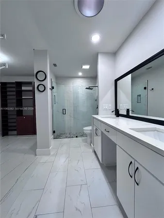 a spacious bathroom with a double vanity sink a toilet and a mirror
