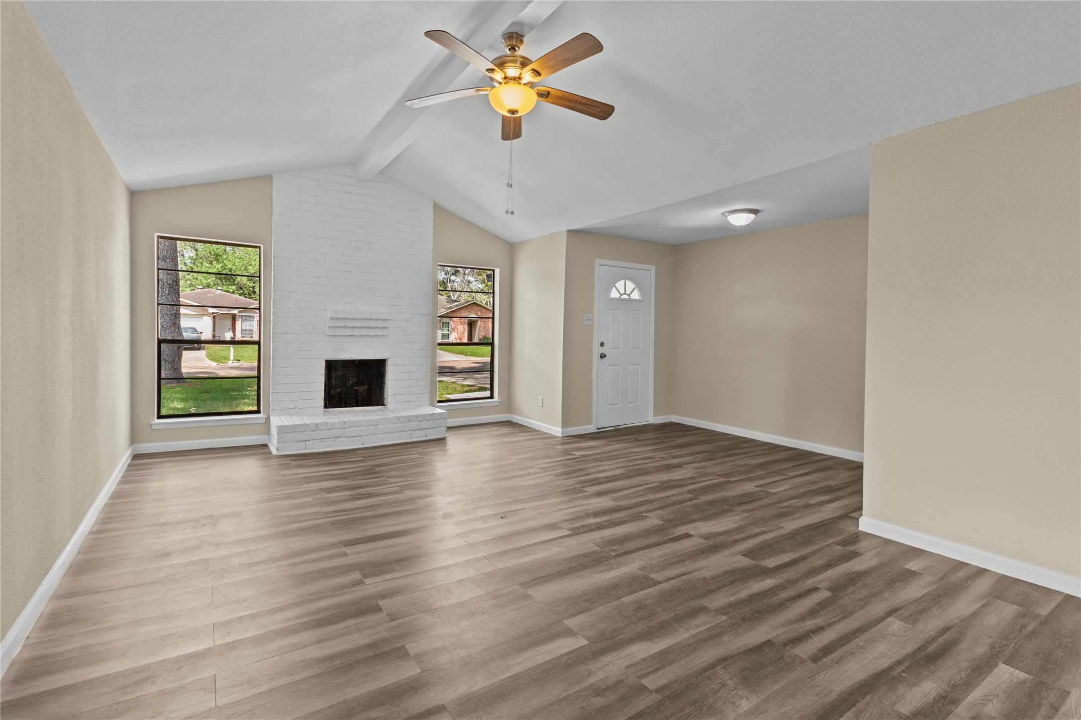 5026 Fitzwater Drive Spring, TX 77373 - Photo 1 of 14 Very open and airy living room with high ceiling, laminate flooring, a grand fireplace. large windows that provide natural light, complementing the neutral walls. Ideal for a cozy, welcoming atmosphere.