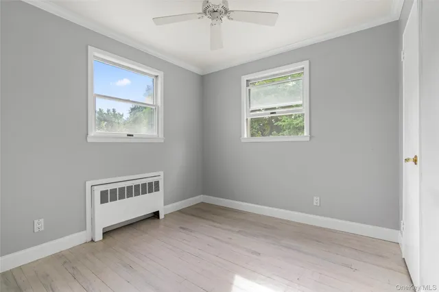 a view of an empty room with wooden floor and windows