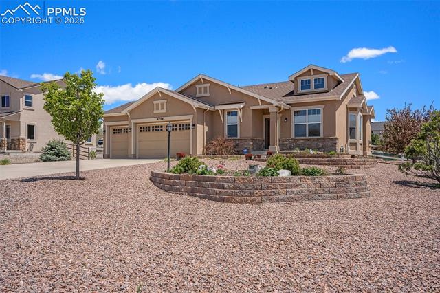 9709 Rockingham Drive Peyton, CO 80831 - Photo 2 of 50 View of front facade featuring stucco siding, an attached garage, stone siding, and driveway