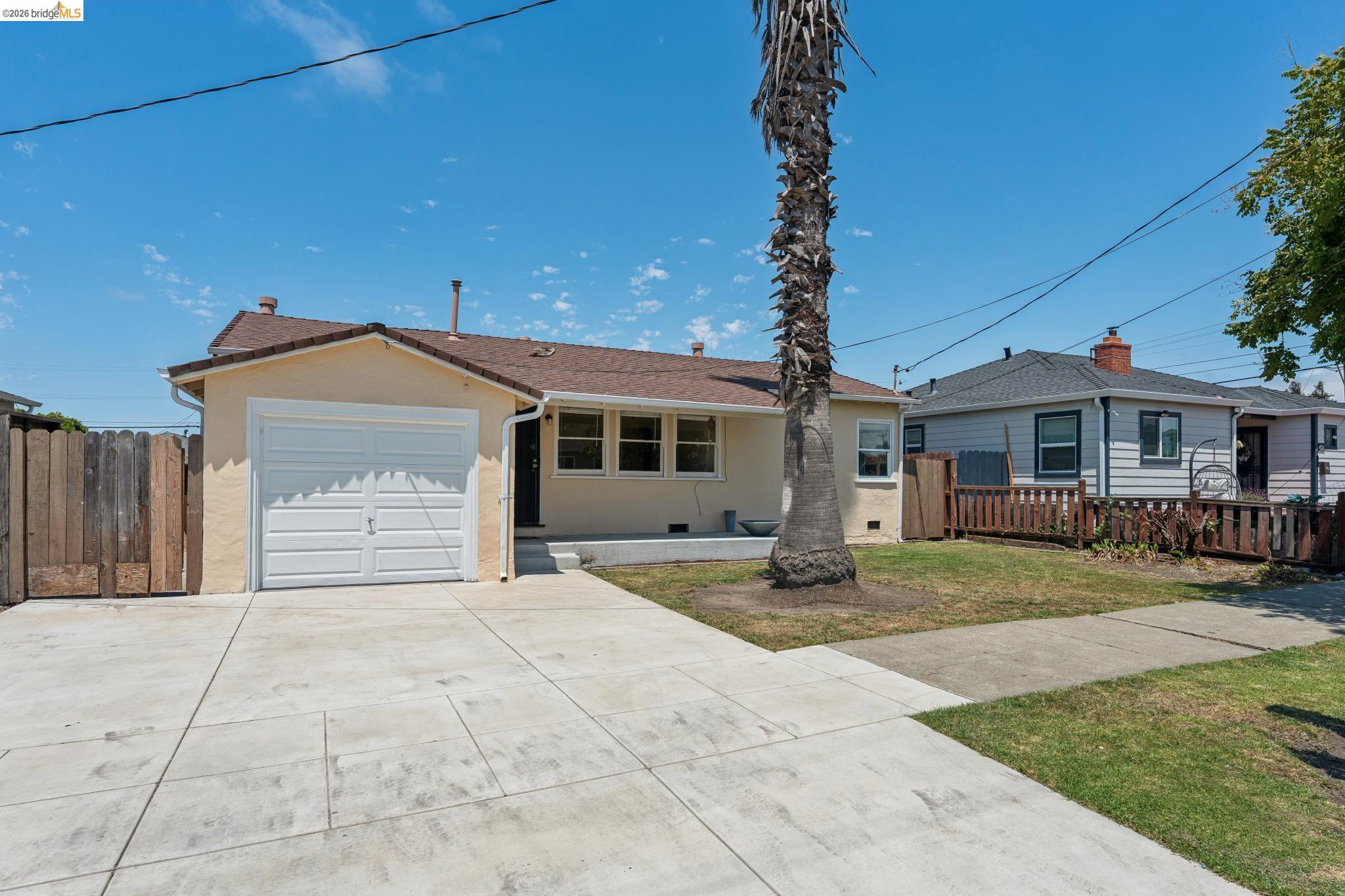 2879 Rheem Avenue Richmond, CA 94804 - Photo 3 of 45 Single-story stucco exterior featuring a front-facing garage, concrete driveway, and a fenced side yard