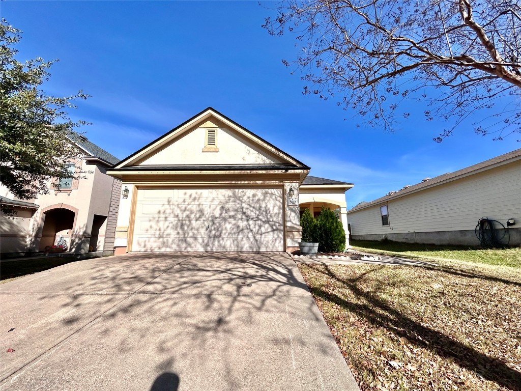 View of front of home featuring driveway, stucco siding, and a garage