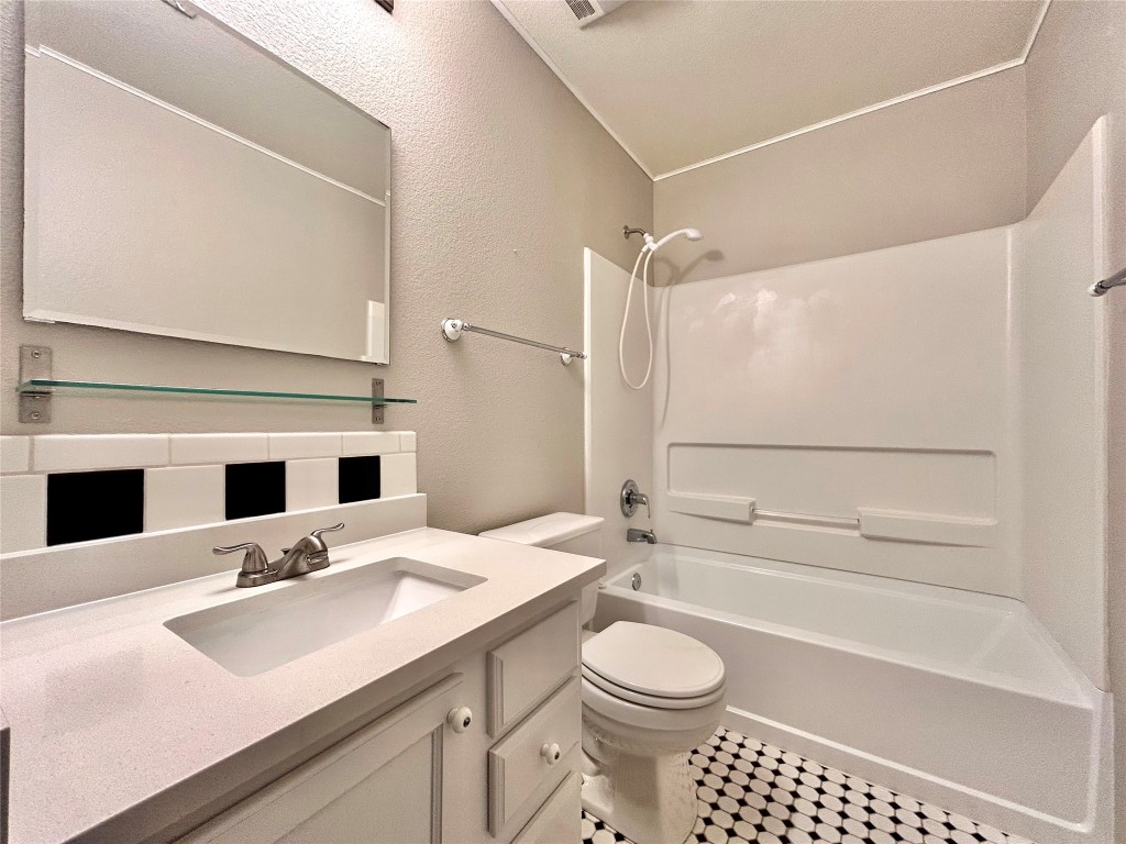 2011 Ashberry Trail Georgetown, TX 78626 - Photo 15 of 24 Bathroom featuring washtub / shower combination, vanity, a textured wall, and backsplash
