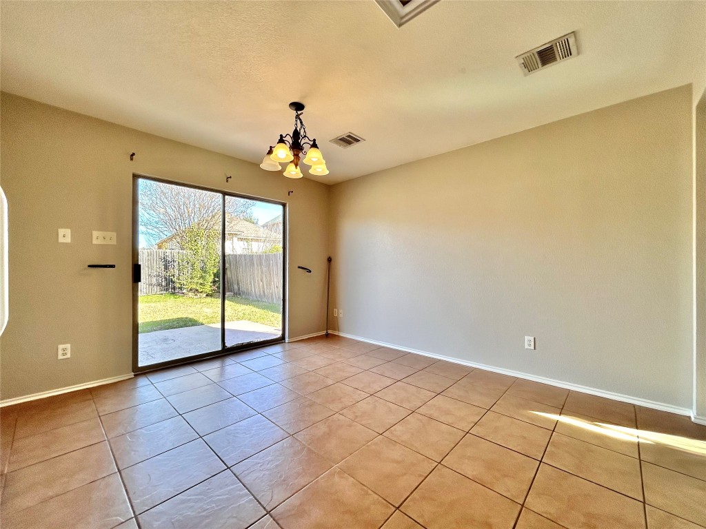 2011 Ashberry Trail Georgetown, TX 78626 - Photo 8 of 24 Unfurnished room featuring a chandelier, light tile patterned flooring, and a textured ceiling