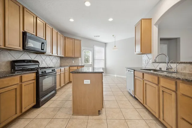 a kitchen with stainless steel appliances granite countertop a stove a sink and a microwave