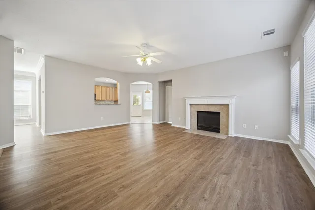 an empty room with wooden floor fireplace and windows
